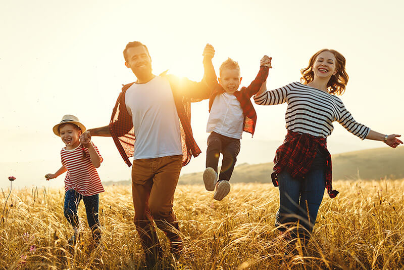 happy family joyfully running through a golden field at sunset.